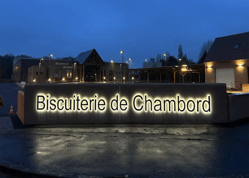 Enseigne lumineuse de la Biscuiterie de Chambord illuminée de nuit.