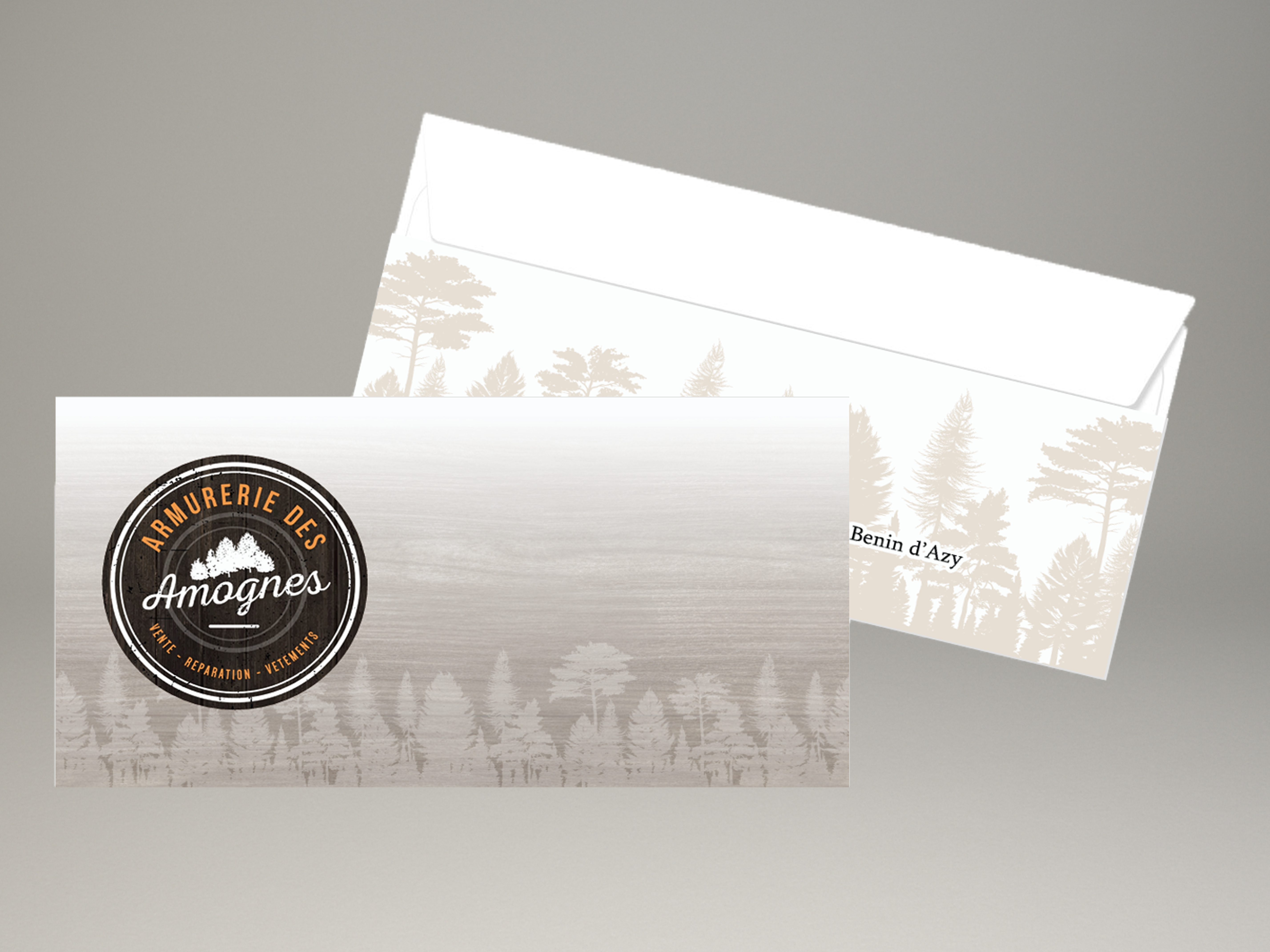Enveloppes personnalisées Armurerie des Amognes avec logo et fond illustré de forêt.